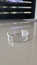 A close-up of a clear, transparent circular glass dish. 