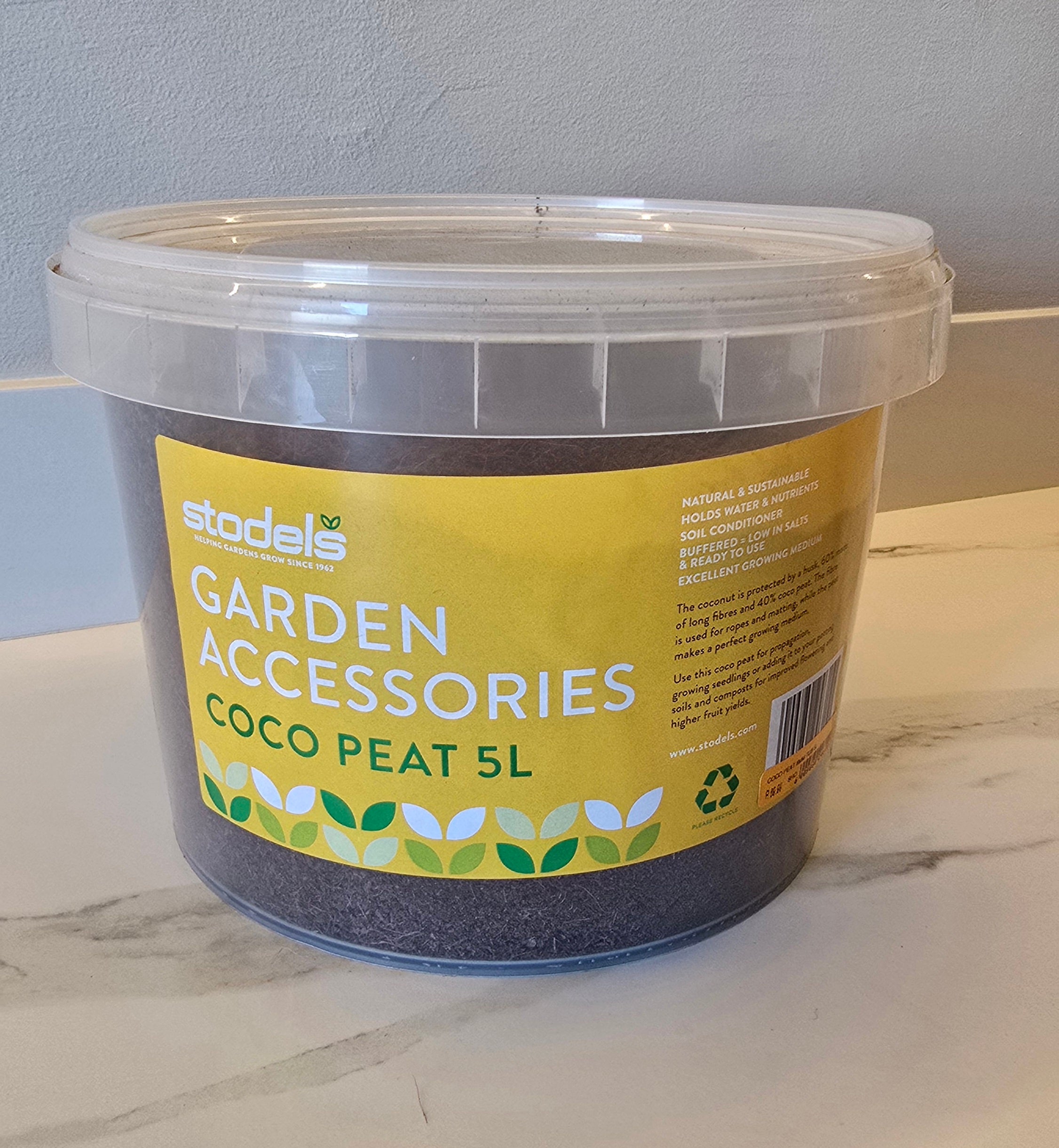 Bucket of coco peat labeled 'Garden Accessories' on a marble surface.